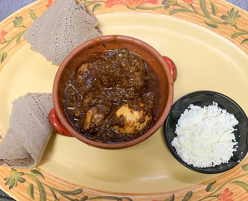 Image: The Signature Doro wat with chicken drums and a hard-boiled egg and a side of ayib (crumbled cheese).
