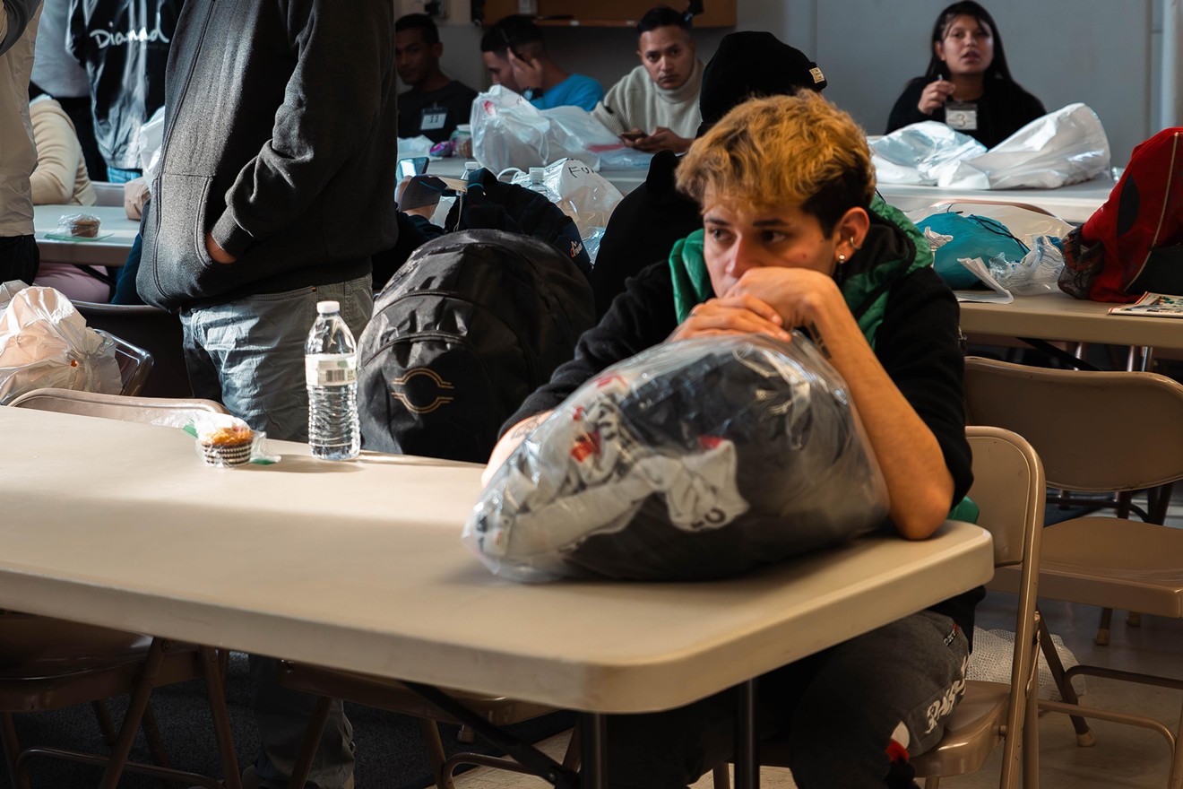 A migrant rests on a small bag of clothes, the only possessions he has, inside of Oak Lawn United Methodist Church.