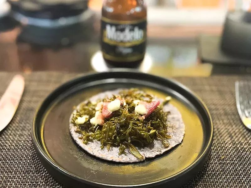 Image: Nopalitos fritos with chunks of bacon on a house-made tortilla with a smear of guacamole.