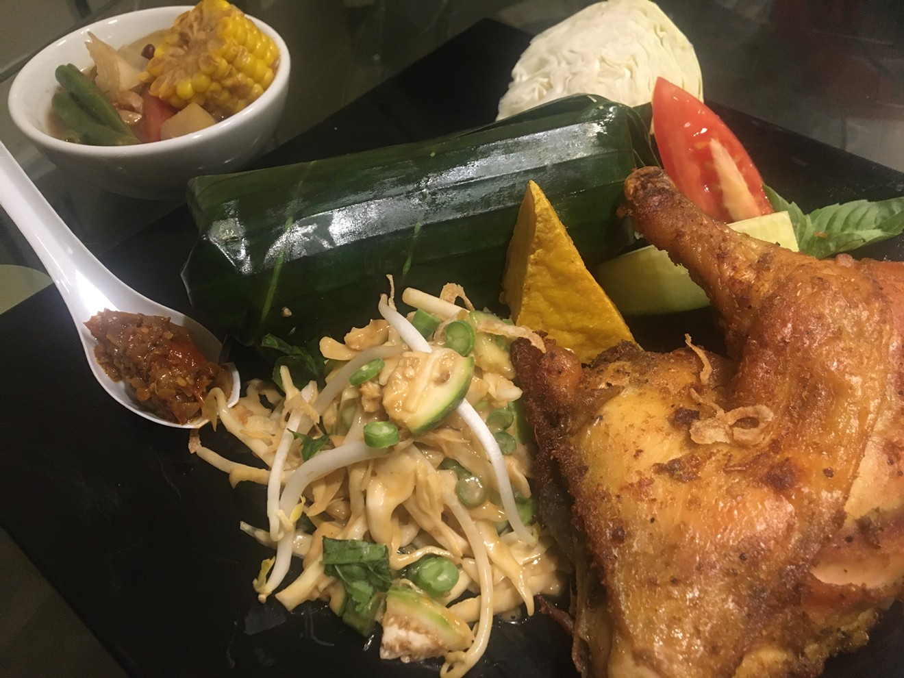 Indonesian fried chicken with rice rolled in banana leaves, fried tofu, corn fritter, lalab, karedok, tamarind soup, onion crackers and sambal