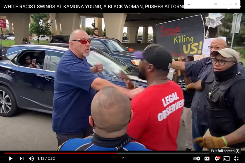 A man raises his fist at attorney Lee Merritt during Sunday's protest in support of Marvin Scott III.