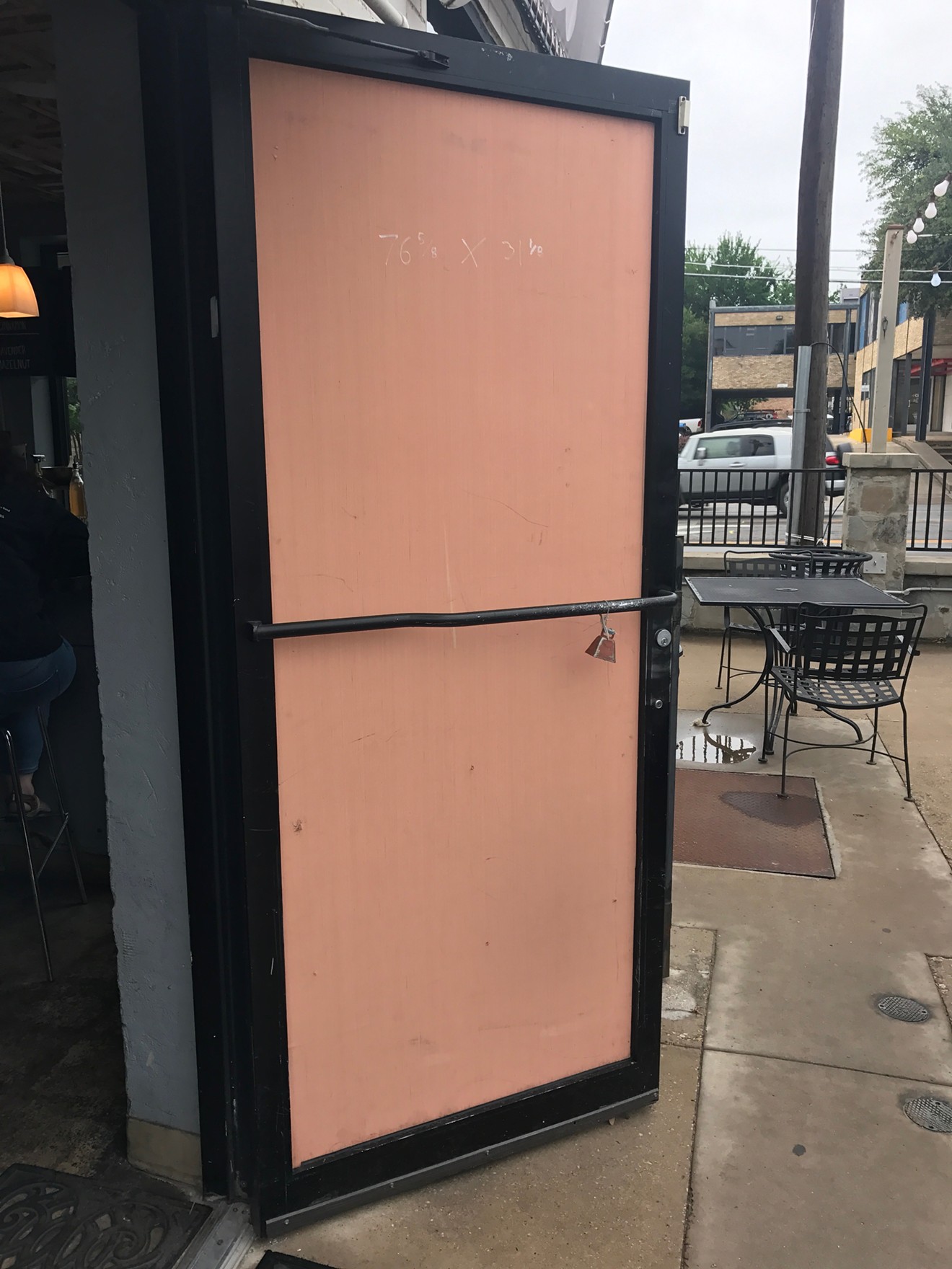 A piece of plywood covers the shattered door at Oak Lawn Coffee.