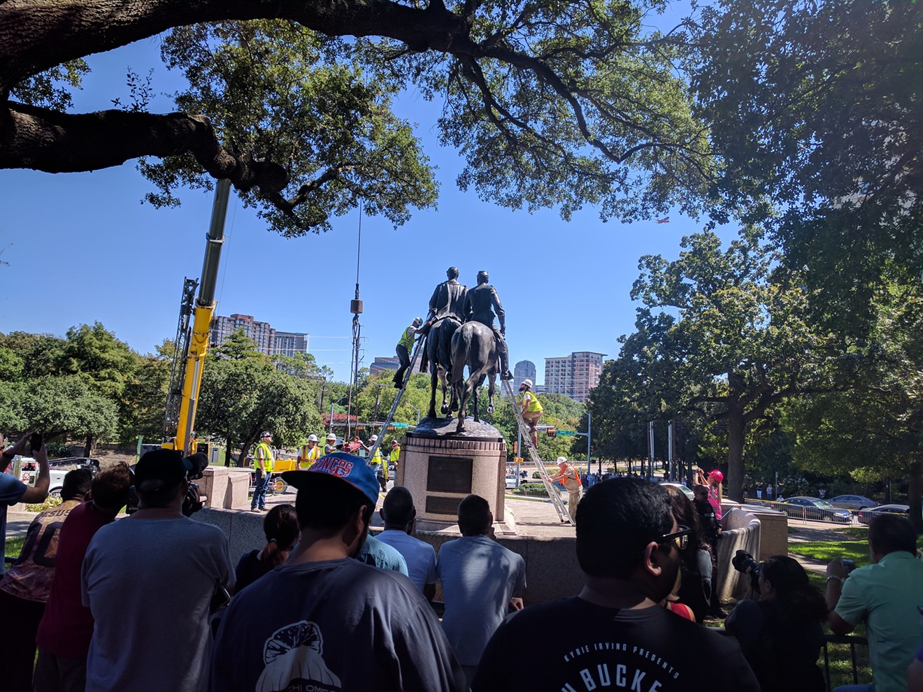 Onlookers watch as workers attach a crane to the Robert E. Lee statue in Lee Park, now called Oak Lawn Park.