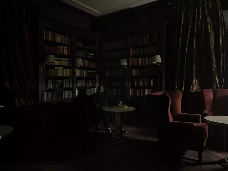 Image: Man sitting in the dark in front of bookshelves