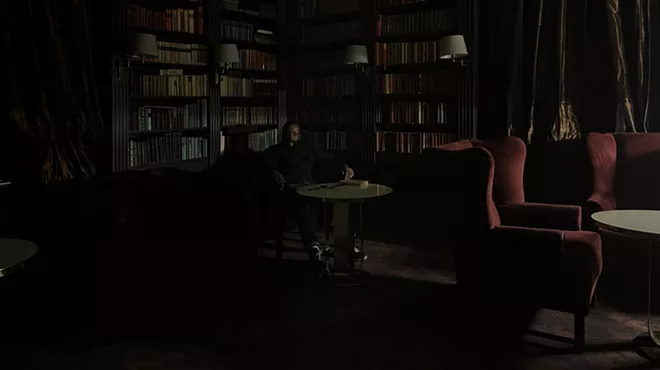 Man sitting in the dark in front of bookshelves