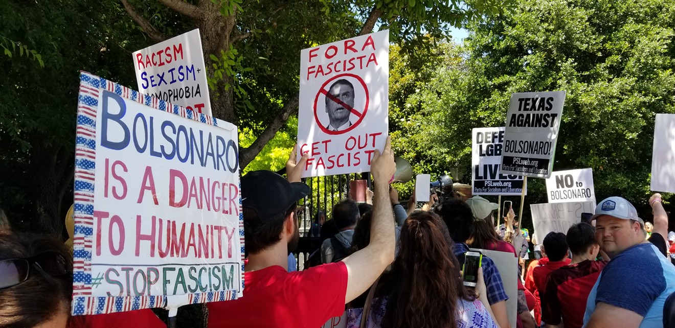 Protesters hold signs denouncing Brazilian President Jair Bolsonaro as a fascist during his visit to Dallas.