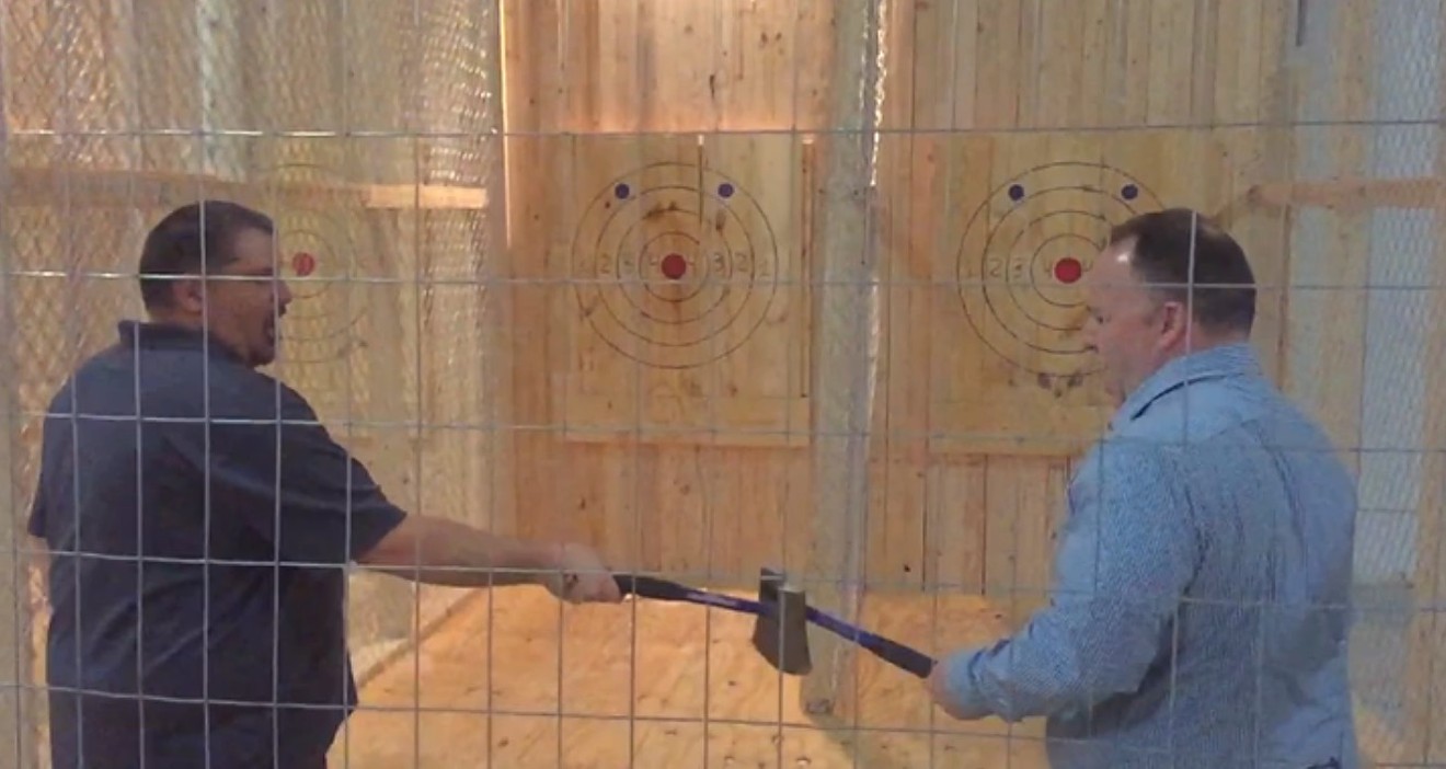 Brad Woodruff (left) and Benjamin Morin slap axes and let out a mighty "lumberjack yell" before tossing their axes at the targets at the Dallas Axe Throwing center.