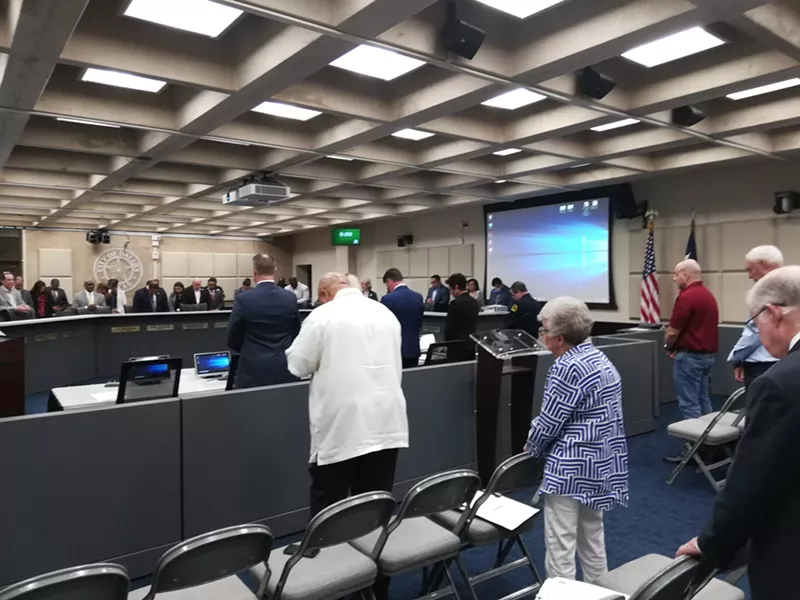 Image: Dallas police Chief U. Renee Hall (fourth from left) prays before the City Council discusses the newly released police staffing study.