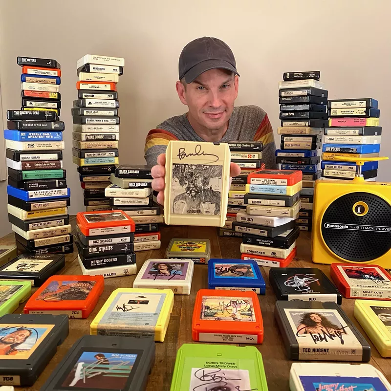 Image: Jason Niebaum shows off his signed collection of 8-track tapes, which keeps growing one concert at a time.
