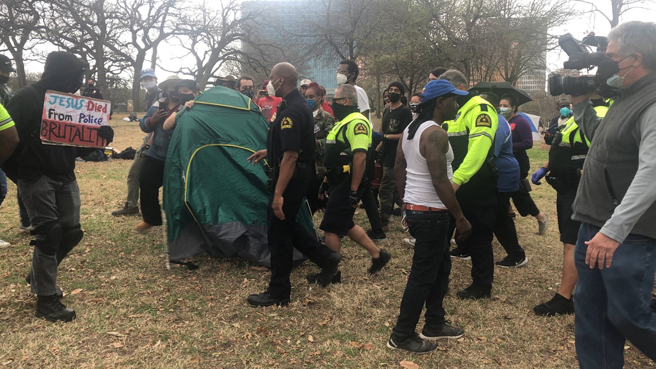 City staff and Dallas Police Department officers sweep a homeless encampment in Pioneer Plaza in March 2021.