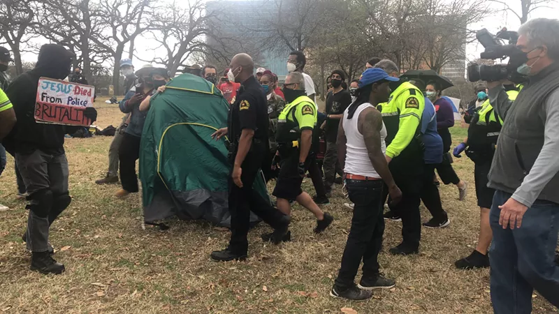 Image: City staff and Dallas Police Department officers sweep a homeless encampment in Pioneer Plaza in March 2021.