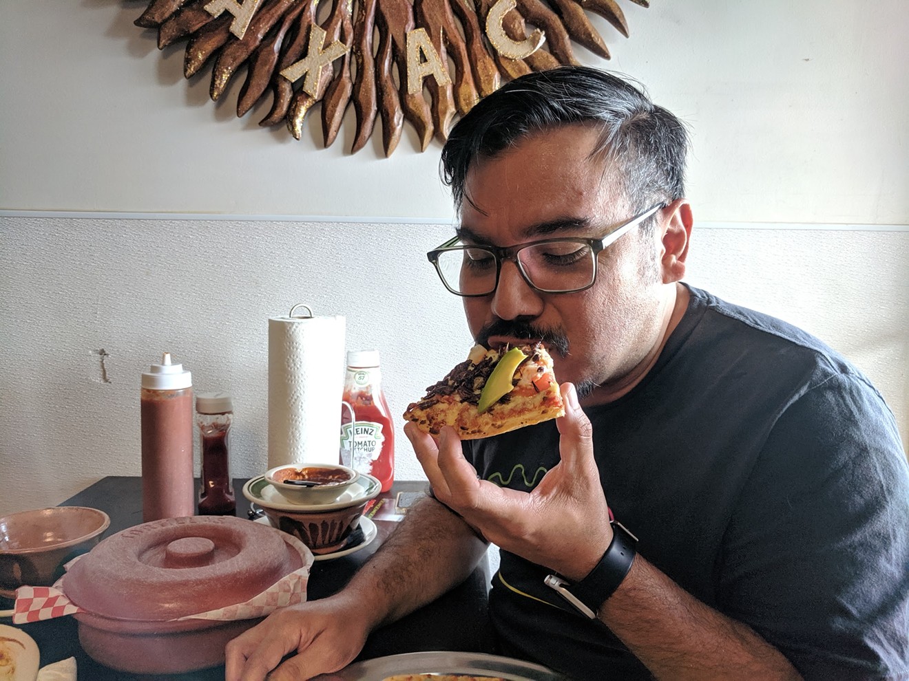 José Ralat, Texas Monthly's new taco editor, chomps down on a slice of Mexican chapulín (grasshopper) pizza.