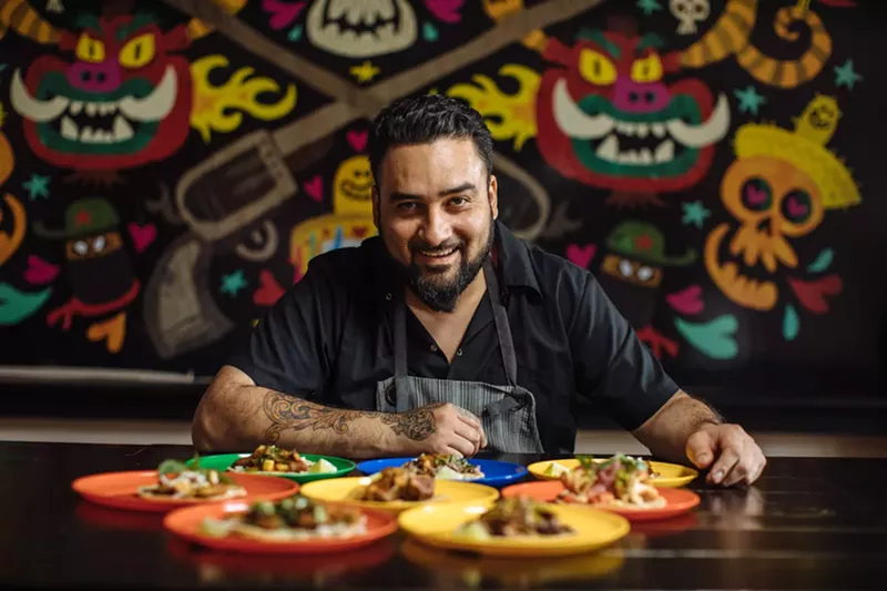 Image: Owner Regino Rojas sits before a spread of tacos in Revolver Taco Lounge.