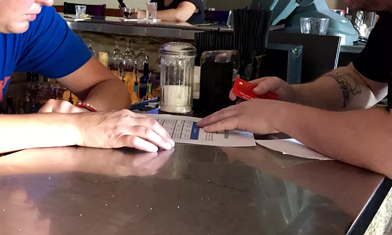 Image: A member of the Democratic Socialists of America's Dallas chapter explains Dallas' new paid sick leave ordinance to a staff member at Sue Elle's on Throckmorton Street in Dallas.