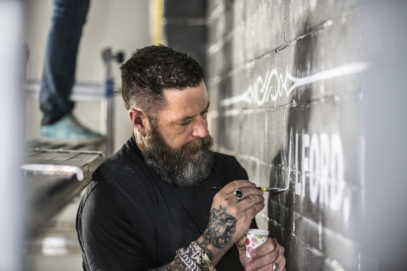 Sean Starr paints letters in his large-scale piece adorning the Dallas gallery's back wall.