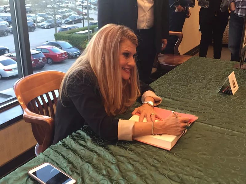 Image: Dianna de la Garza signs a copy of her new memoir, Falling with Wings: A Mother's Story, about her family's experiences with mental illness and domestic abuse.