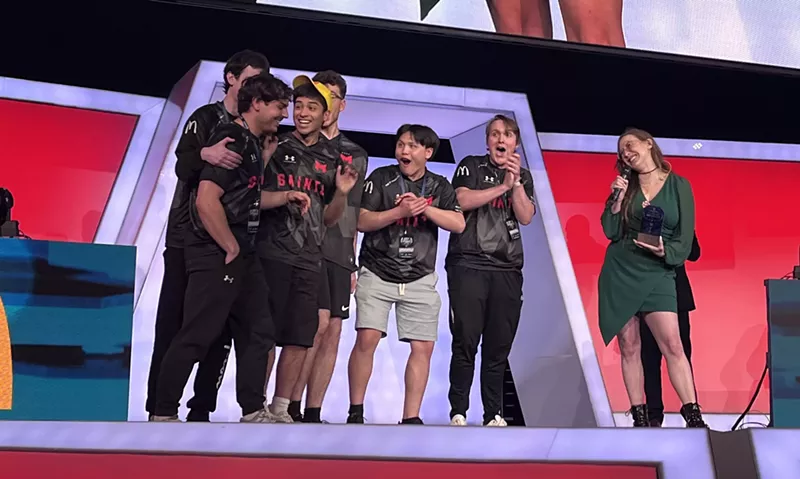 Image: Enrique "Joobi' Triana, left, steps forward to accept his MVP trophy after his Maryville University team won the Overwatch 2 Grand Finals at the Collegiate Esports Commissioner's Cup in Arlington on Sunday.