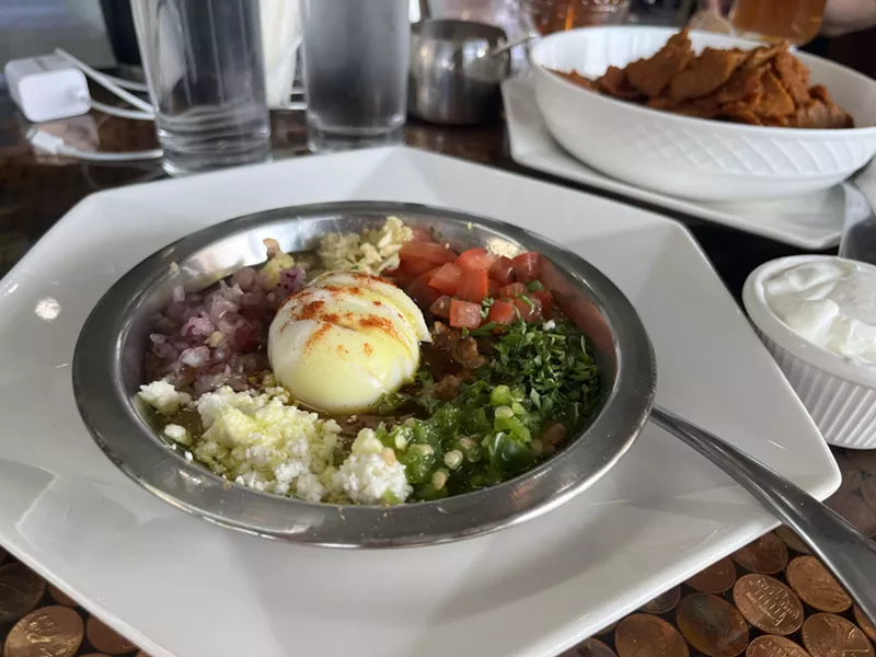Image: A creamed fava bean dish, the traditional Fuul is topped with items like tomato, garlic and boiled eggs.