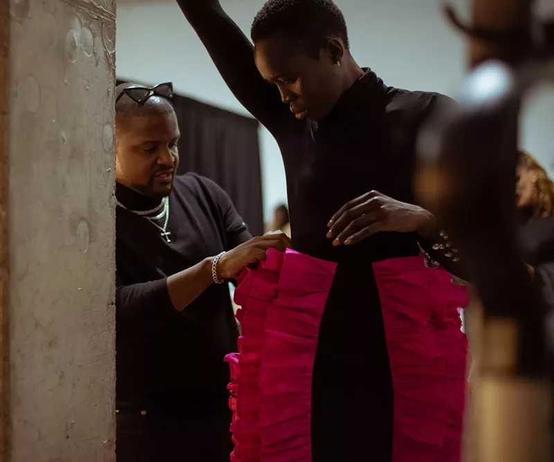 Image: Project Runway alum Venny Etienne, left, fitting a model with one of his designs.