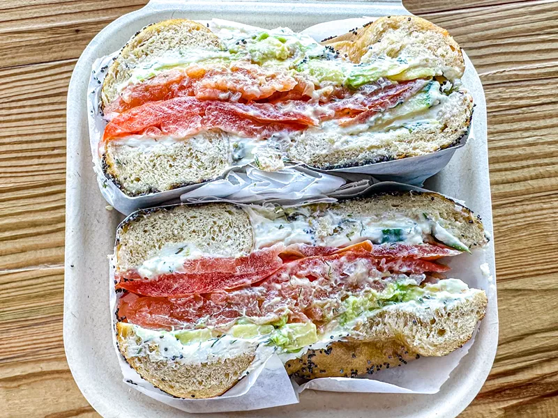 Image: The Williamsburg: Acme Nova Lox, plain CC, avocado, red onion, tomato, cucumber and capers on a poppy seed bagel.