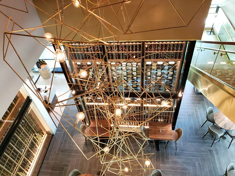 Image: Looking down from upstairs gives you a dizzying yet glorious view of the staircase, chandelier and wine tower inside Perry's new location.