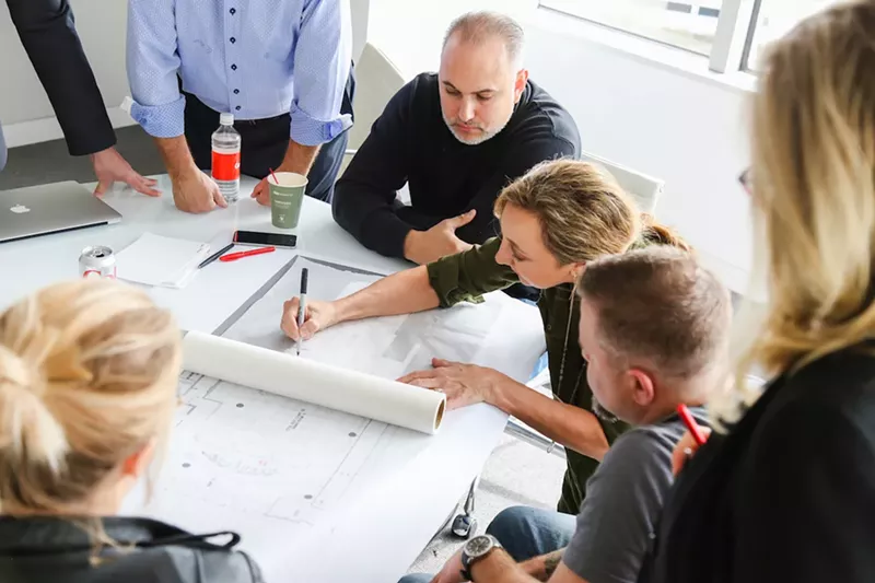 Image: Josh Babb, center, creator and co-owner of Rock Libations, works with Dana Foley’s design team on plans for Musume.