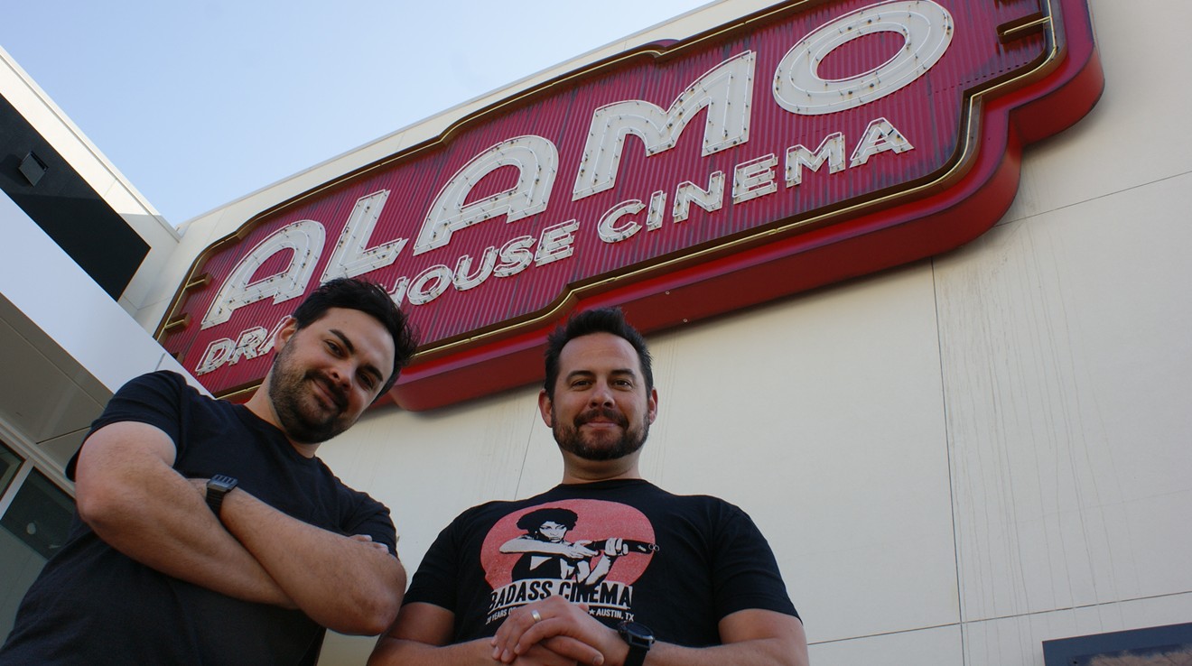 Alamo Drafthouse DFW creative director James Wallace (left) and chief operating officer Bill DiGaetano stand in front of the 20-by-40-foot neon sign for the chain's newest movie theater in the Toyota Music Factory in Irving.