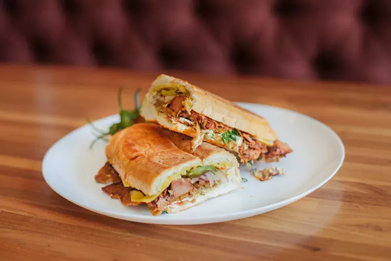 Image: Mojo-style seitan from BE-Hive, smoked jackfruit and vegan provolone with an aji chili crema, pickles, shaved red onion and relish for $17