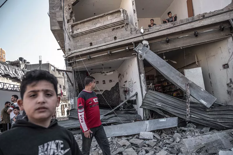 Image: Survivors move through rubble following Israeli bombings in Gaza, which have left nearly 250 Palestinians dead.