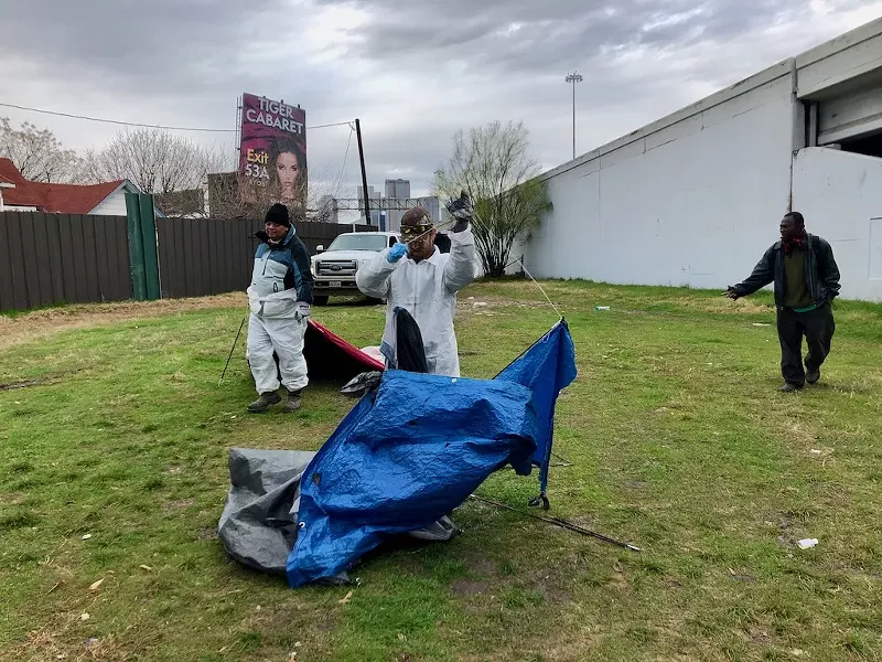 Image: City contractors tore down a homeless encampment next to Interstate 30 on Tuesday.