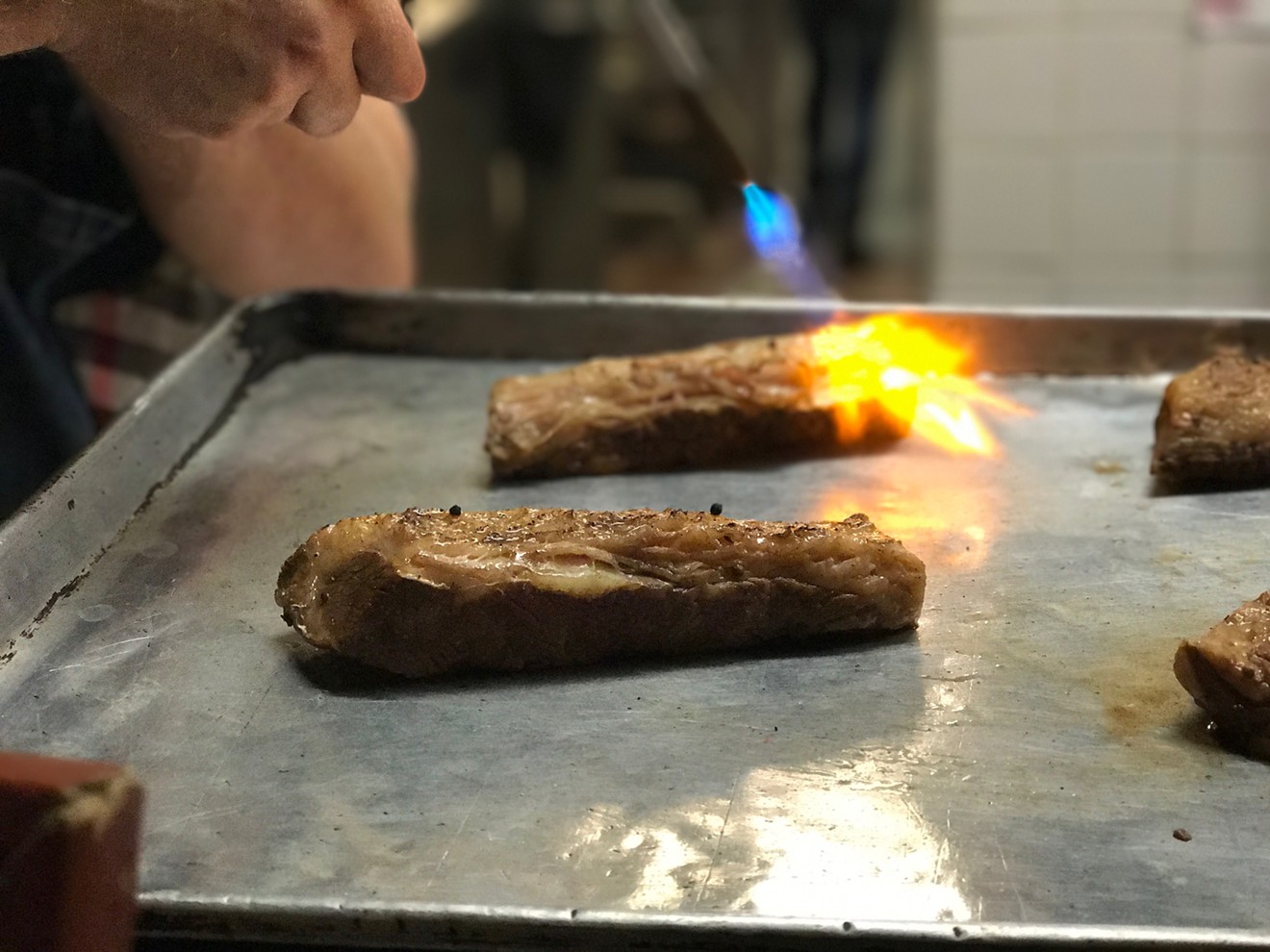 Chef David Anthony Temple uses a torch to sear sous vide Kobe beef that's been spritzed with a tincture made of Everclear and White Widow, a strain of marijuana, at an underground cannabis dinner recently held in Dallas.