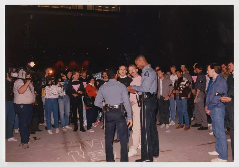 Image: A GUTS activist speaks with police after drawing a chalk outline to represent someone who had died of AIDS related complications.