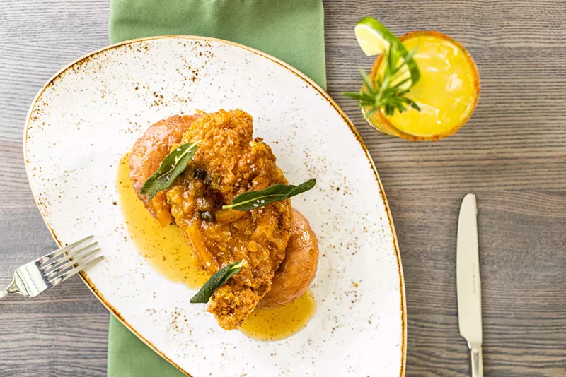 Image: Fried chicken and served over glazed cake doughnuts with jalapeno-orange preserves and fried sage.