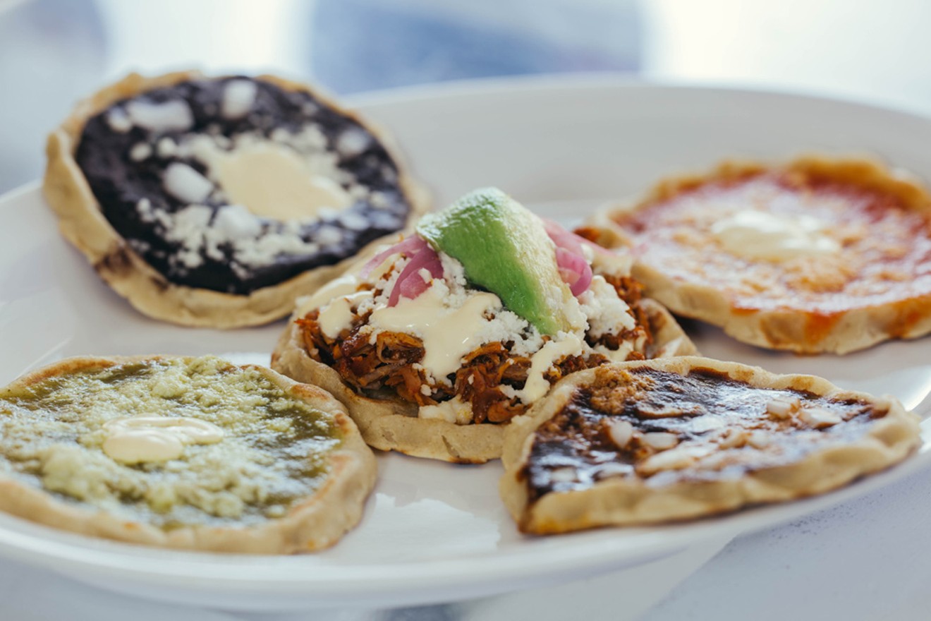 A platter of picadas:  soft masa discs topped with different colors of salsa, black beans, pork