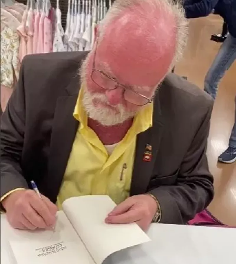 Image: Author Shawn Warner autographs a copy of his book Leigh Howard and the Ghosts of Simmons-Pierce Manor at a Kroger store in Dallas for a TikTok video.