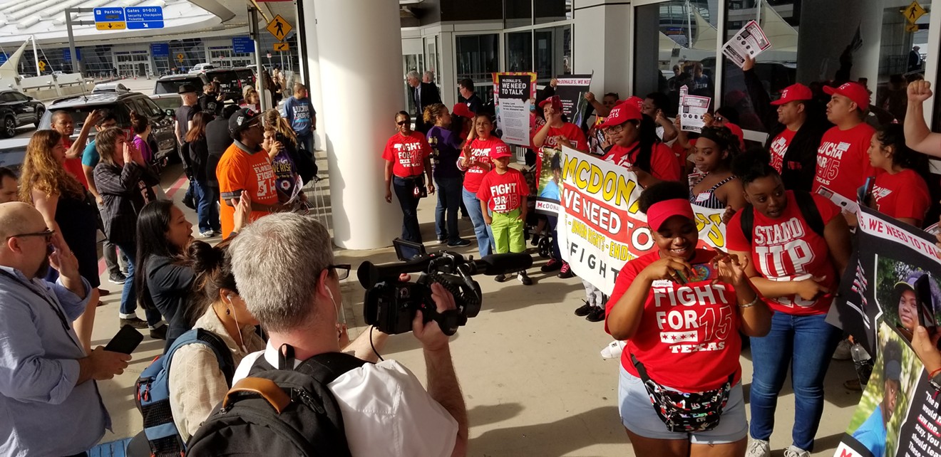 McDonald's employee Bleu Rainer (left, orange shirt) leads fellow workers in a show of unity Thursday morning outside the Grand Hyatt at D/FW International Airport. McDonald's workers demonstrated at the annual shareholders meeting.