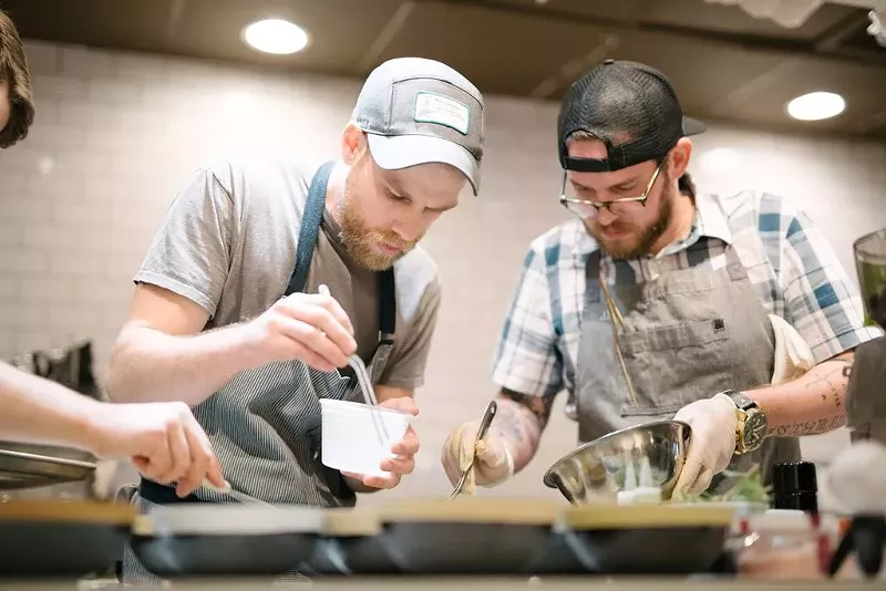 Image: Jeremy Hess and Josh Farrell cook together at the farmer-focused spring pop-up dinner at Trio Craft Coffee.