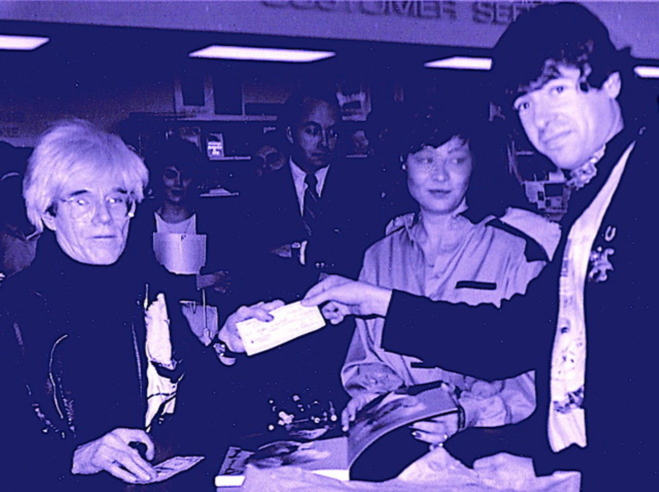 The author (right) hands Andy Warhol (left) a million dollar check during an ’85 book signing at Taylor Books on Preston Road.
