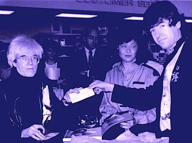 Image: The author (right) hands Andy Warhol (left) a million dollar check during an ’85 book signing at Taylor Books on Preston Road.