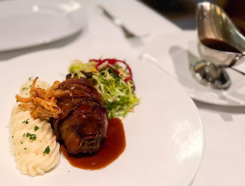 Image: The bacon-wrapped meatloaf comes with a side of whipped russets and a gravy boat.
