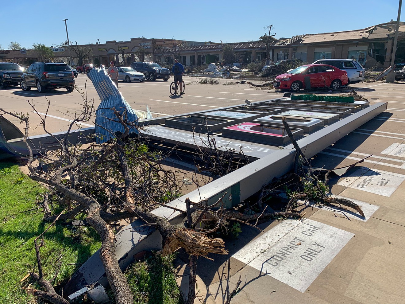 A sign for the shopping center on the southeast corner of Preston Road and Royal Lane lays flat from Sunday's tornado. In this same corner are dramatically damaged businesses, including Fish City Grill.