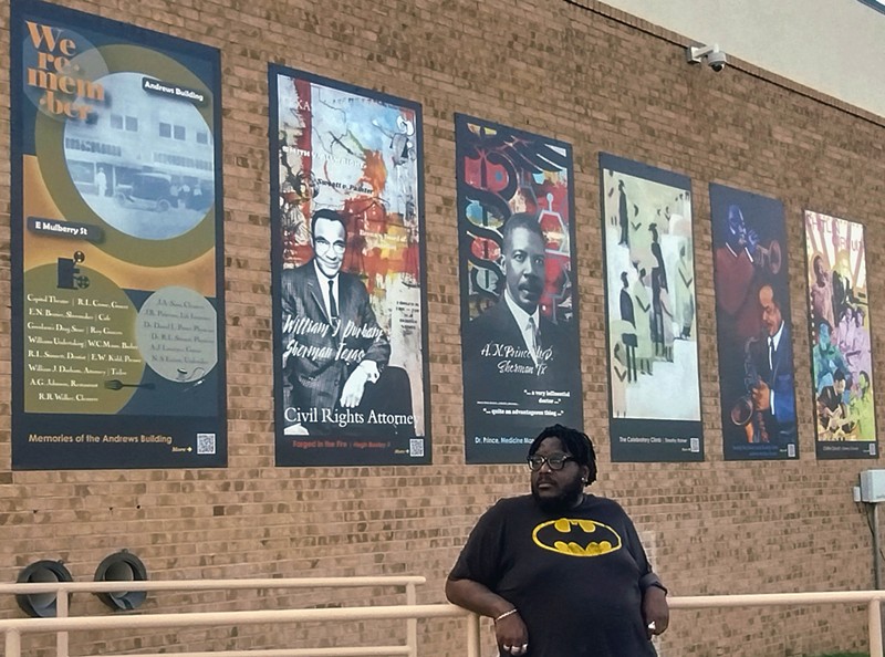 Artist Hugh Baxley in front of the murals commissioned by the Sherman Cultural District.