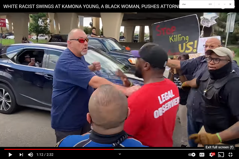 Image: A man raises his fist at attorney Lee Merritt during Sunday's protest in support of Marvin Scott III.
