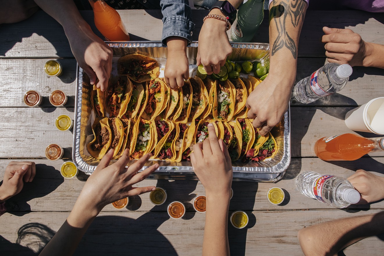 Friends grab tacos from a take-out tray at Trompo in Oak Cliff.