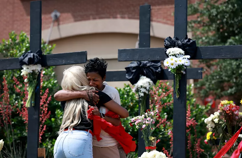 Image: Mourners hug as they visit a memorial near the scene of a mass shooting at the Allen Premium Outlets mall.
