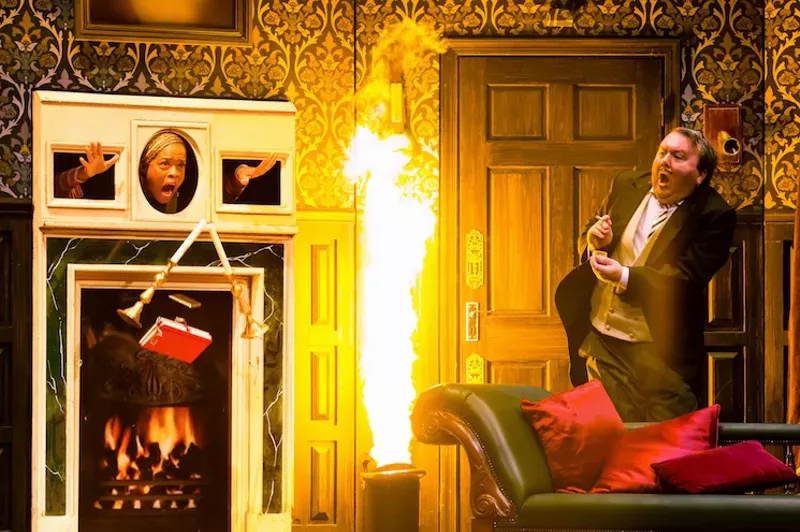 Image: Dennis (right), played by Scott Cote, accidentally ignites a flammable liquid and startles the stage hand Annie, played by Angela Grovey, who's standing in for a fireplace mantle in the slapstick comedy The Play That Goes Wrong.