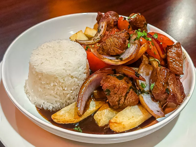 Image: Lomo saltado: wok stir-fried beef tenderloin strips, onions, tomatoes, cilantro and potatoes with rice.