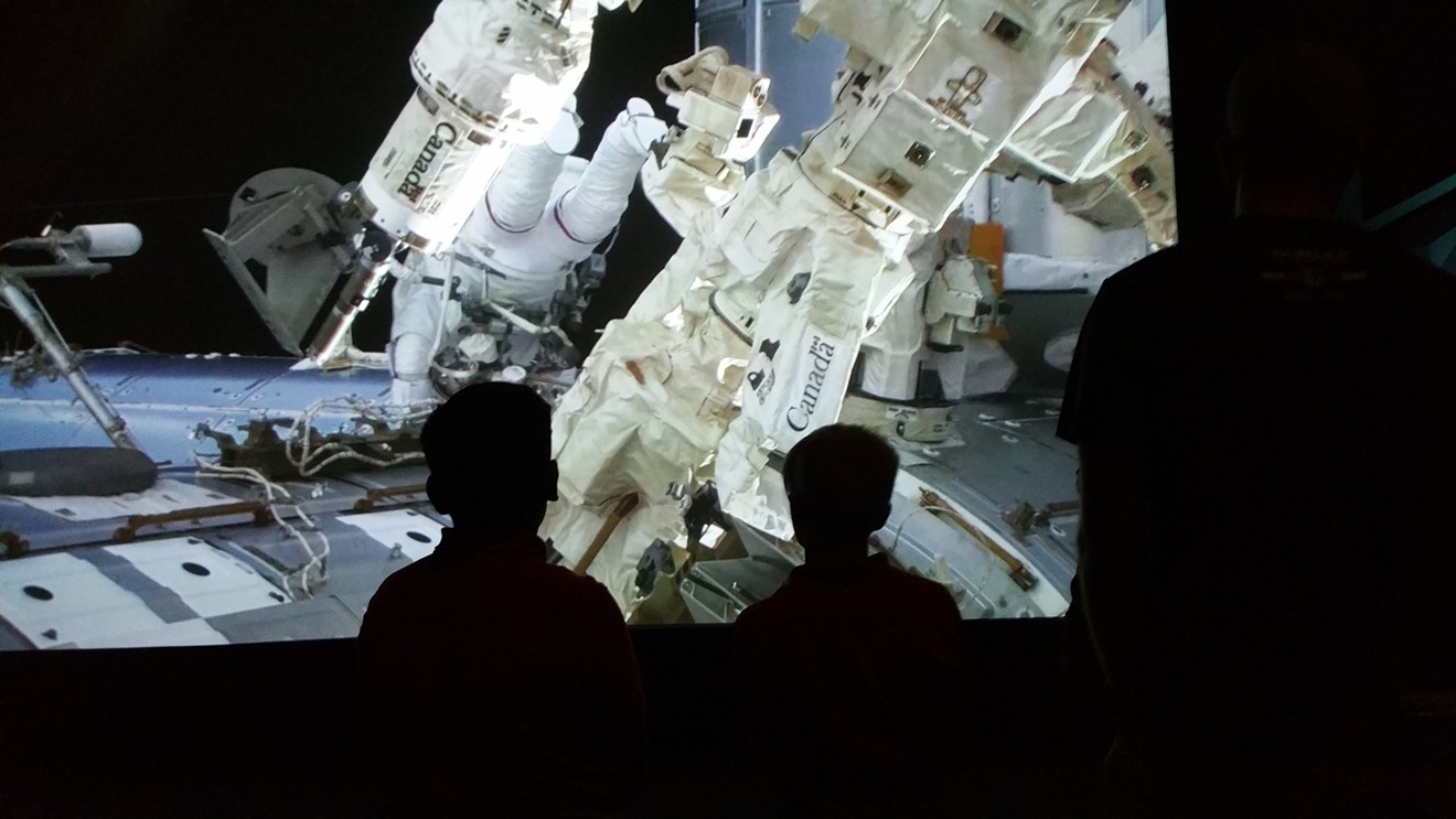 A pair of students watch footage from the International Space Station while visiting the Perot Museum of Nature and Science.