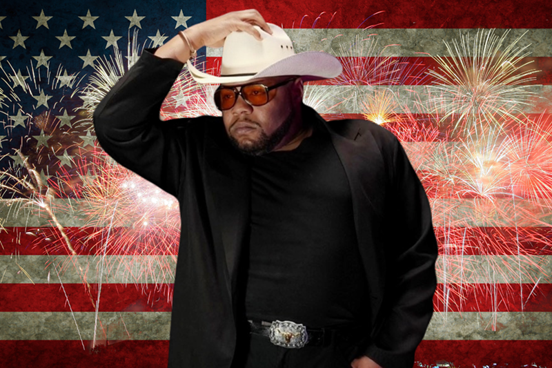 Image: Man standing in front of an American flag with a cowboy hat