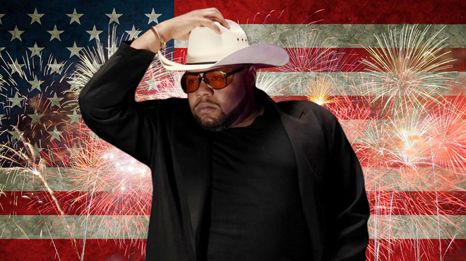 Man standing in front of an American flag with a cowboy hat